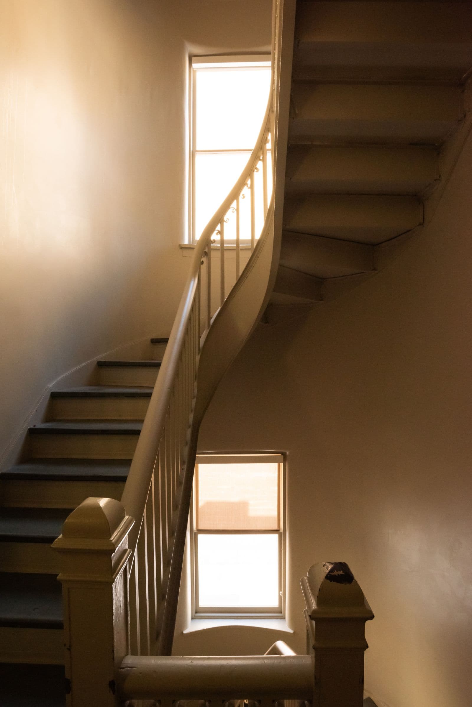 Curved wooden staircase with painted balusters in warm light