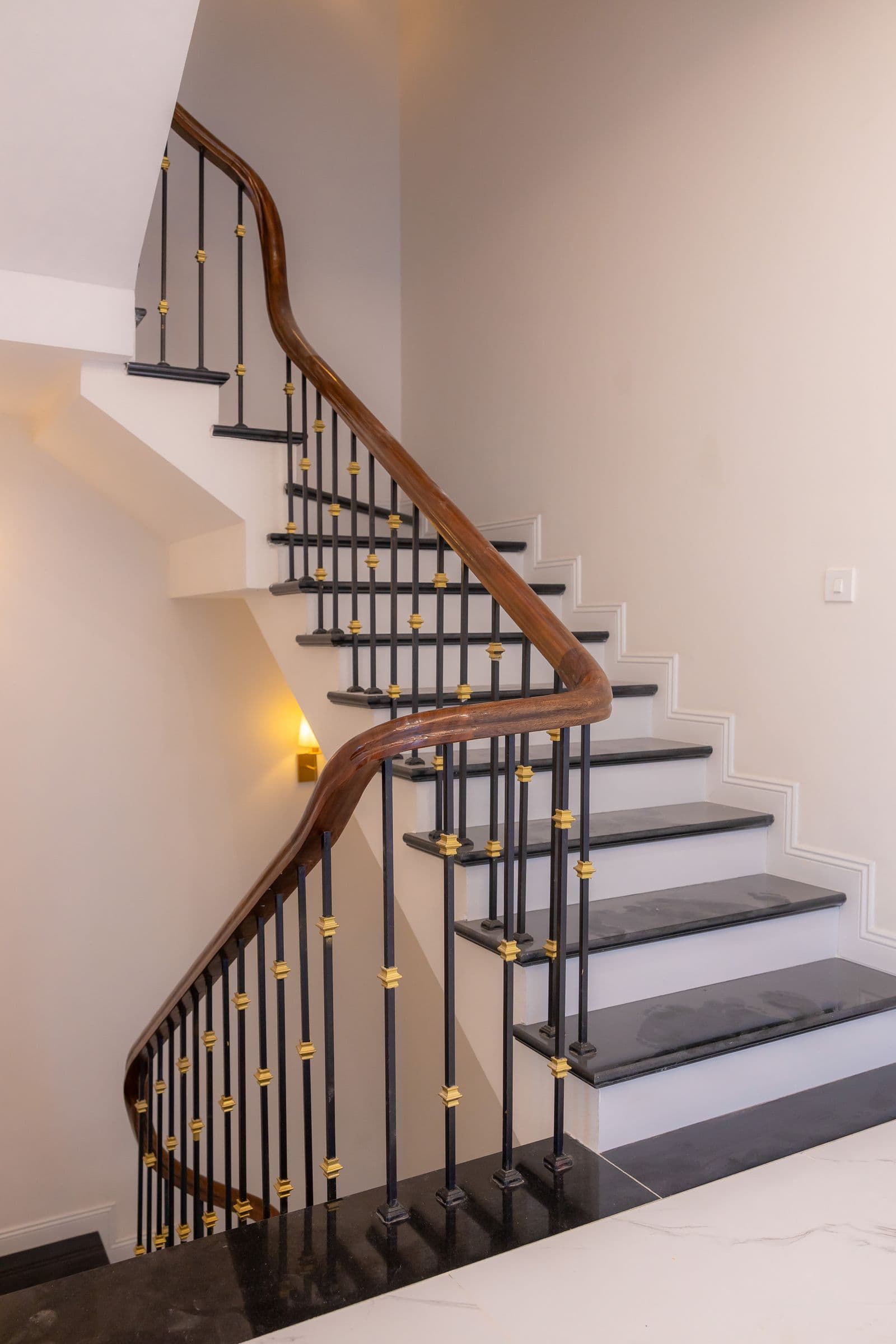 Wooden handrail with decorative iron balusters on white stairs